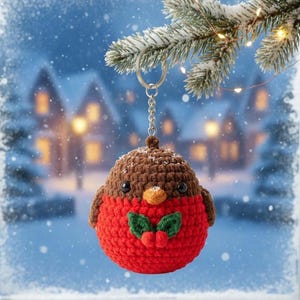 May include: A handmade crocheted robin keyring. The bird has a red body, brown head, and small black eyes. It features an orange beak and green holly leaves with red berries. The keyring hangs from a silver chain, ideal for festive decorations.