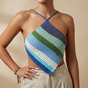 Puede incluir: Top halter de ganchillo con un diseño de rayas diagonales en tonos azules, verdes y blancos. El top tiene forma cuadrada y tirantes cruzados en la nuca. El tejido de ganchillo tiene un aspecto texturizado.