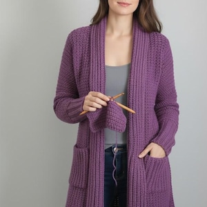 Può includere: Cardigan lungo in maglia viola con collo a scialle e due tasche anteriori. Il cardigan è lavorato a maglia con ferri di legno. Il capo è di media lunghezza e le maniche sono lunghe. Il cardigan è di colore unito.