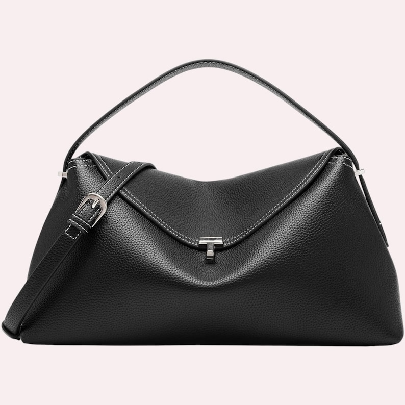 May include: A black leather handbag with a top handle and a detachable shoulder strap. The bag features a silver-tone buckle and a clasp closure. White stitching accents the edges of the bag.