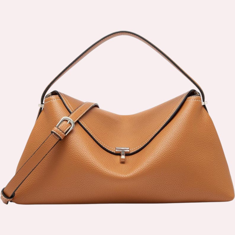 May include: A tan leather handbag with a top handle and a detachable shoulder strap. The bag features a flap closure with a silver-tone clasp and a textured surface. The bag's design is a trapezoid shape.