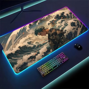 Puede incluir: Alfombrilla de ratón rectangular para juegos con una ilustración de estilo anime de un hombre y olas del océano. La alfombrilla tiene un borde LED de colores, un teclado y un ratón.