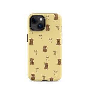 May include: A yellow phone case featuring a repeating pattern of brown teddy bears and small bows. The case has a camera cutout and black side buttons.