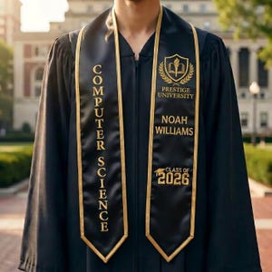 May include: Black graduation gown with gold trim and a Computer Science sash. The sash displays "COMPUTER SCIENCE" vertically, the university logo, the name "NOAH WILLIAMS", and "CLASS OF 2026" in gold lettering.