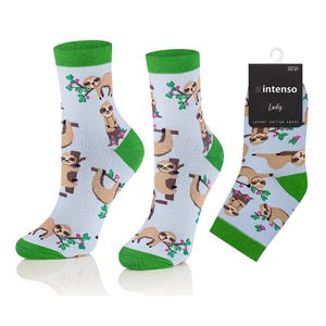May include: Three pairs of light blue socks featuring a repeating pattern of brown sloths on green leafy branches. The socks have green cuffs and toes. One pair has a black tag that reads "intenso Lady LUXURY COTTON SOCKS".