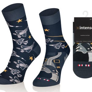 May include: Two navy blue socks with a jet plane and star pattern. The socks have a dark blue cuff and heel. A black tag with the brand name "intenso" is attached to one sock.