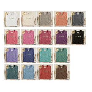 Pu&ograve; includere: Una collezione di t-shirt Comfort Colors in vari colori, tra cui bianco, avorio, kaki, terracotta e pepe. Ogni maglietta presenta un design floreale e il testo "Kindness".