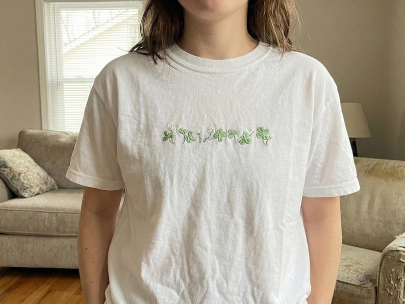 Pu&ograve; includere: T-shirt bianca con trifogli verdi ricamati e la scritta "124". La maglietta a maniche corte &egrave; realizzata in un materiale morbido e confortevole. Il disegno &egrave; centrato sul petto.