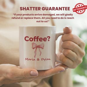 May include: White ceramic mug with the text "Coffee?" in burgundy, along with a burgundy bow graphic and the names "Maria & Dylan." The mug has a handle and is held by a person. The image also includes the text "SHATTER GUARANTEE."