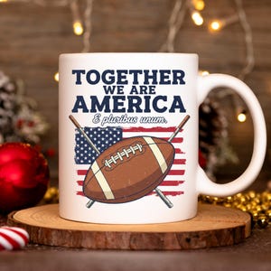 Könnte beinhalten: Weiße Keramik-Tasse mit Football- und amerikanischem Flaggen-Design. Die Tasse trägt den Text "TOGETHER WE ARE AMERICA & e pluribus unum". Zwei gekreuzte Fahnenmasten befinden sich hinter dem Football.