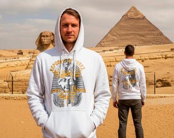 Pode incluir: Moletom branco com capuz com um gráfico frontal de uma máscara de faraó egípcio e o texto "REPUBLIC OF EGYPT". A parte de trás do moletom também apresenta o mesmo gráfico. O fundo inclui a Esfinge e uma pirâmide.