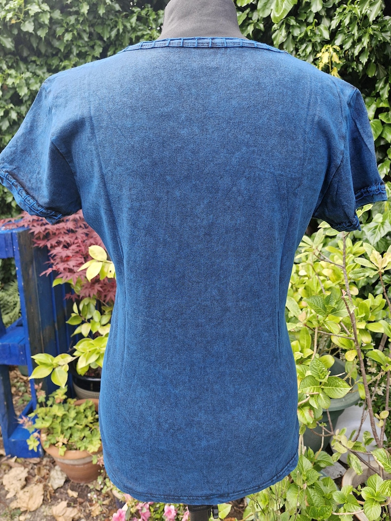 May include: A short-sleeved t-shirt in a dark blue acid-wash finish. The garment features a round neckline with a ribbed trim and matching ribbed detailing on the sleeve cuffs. The fabric has a mottled, textured appearance throughout the surface.