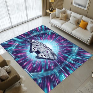 Puede incluir: Una alfombra rectangular con un diseño de nave espacial en tonos grises, sobre un fondo vibrante de líneas azules, rosas y moradas que irradian hacia afuera. El diseño de la alfombra evoca una sensación de velocidad y viaje futurista.
