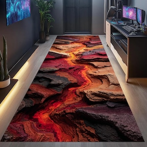 Puede incluir: Una alfombra rectangular y larga con un diseño de cañón en 3D. La alfombra presenta una vibrante paleta de colores rojos, naranjas, marrones y grises, creando una apariencia texturizada y realista. El diseño se asemeja a un río de lava que fluye a través de un cañón.