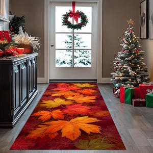 Può includere: Un tappeto runner rettangolare con un motivo di grandi foglie d'acero autunnali colorate in rosso, arancione e giallo. Il tappeto è posto in un corridoio con un albero di Natale e una ghirlanda sulla porta.