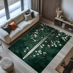 May include: A rectangular area rug with a dark green background featuring a stylized sword design intertwined with flowering branches. The sword is silver, and the flowers are white. The rug is placed in a living room setting.