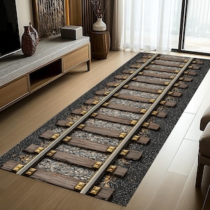 Puede incluir: Una alfombra rectangular con un dise&ntilde;o de v&iacute;a de tren. La alfombra presenta traviesas de madera, grava gris y rieles plateados con fijaciones doradas. La alfombra est&aacute; sobre un fondo gris oscuro.