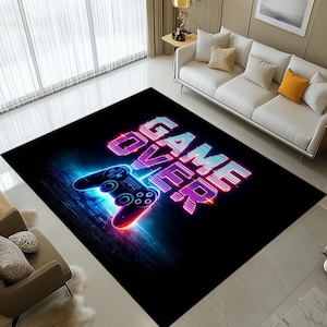 Pode incluir: Tapete retangular preto com um design "GAME OVER" em estilo neon. O tapete apresenta um gráfico de controlador azul e vermelho brilhante. O texto e o controlador têm uma estética digital vibrante, ideal para uma sala de jogos.