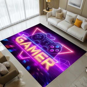 May include: A rectangular rug with a neon design. The rug features the word "GAMER" in yellow, with a game controller graphic. The background is a mix of purple, pink, and blue geometric shapes, creating a modern, tech-inspired aesthetic.