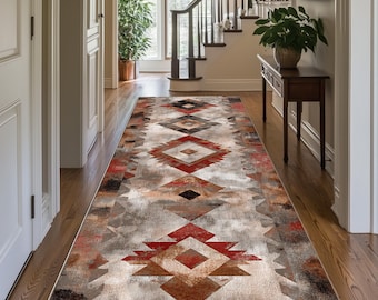 May include: A long, rectangular rug with a Southwestern geometric pattern in shades of red, brown, gray, and black. The rug is placed in a hallway with hardwood flooring and a staircase in the background.