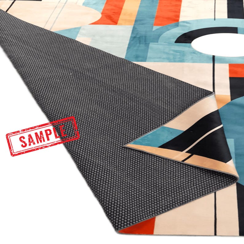 May include: A modern area rug with a geometric design featuring shapes in teal, orange, black, and beige. The rug's underside is a dark gray, textured material. The word "SAMPLE" is stamped in red on the rug.