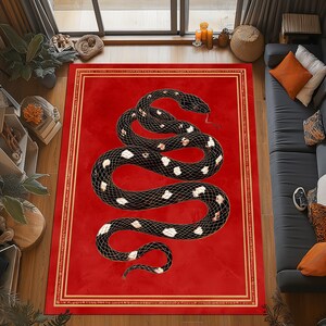Puede incluir: Una alfombra roja con un diseño de serpiente negra y marcas blancas y crema. La serpiente está enrollada sobre un fondo rojo con un borde dorado. Un accesorio decorativo para el hogar.
