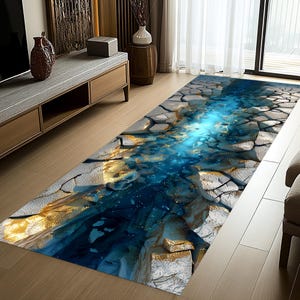 May include: A rectangular area rug with a 3D cracked earth design. The rug features a blue, gold, and gray color scheme, with a central blue river-like pattern. The design gives the illusion of depth and texture, suitable for home decor.