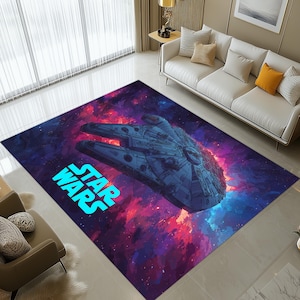 May include: A rectangular area rug featuring a detailed illustration of the Millennium Falcon spaceship against a vibrant, colorful nebula background. The words "STAR WARS" are displayed in bright blue. The rug is designed for indoor use.