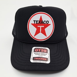 May include: Black trucker hat with a red and white Texaco logo on the front. The hat features a mesh back and a curved brim. The hat has the text "OTTO" and "TRUCKER" on a tag.
