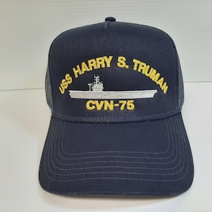 May include: Navy blue trucker hat with the text "USS HARRY S. TRUMAN CVN-75" embroidered in yellow and white. The hat features a mesh back and a curved brim.
