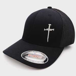 May include: Black Flexfit baseball cap with a white embroidered cross design. The cap features a curved brim, a mesh back, and a Flexfit sticker. The cap is a classic style, suitable for everyday wear.