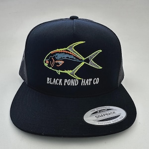 May include: Black snapback hat with a fish design embroidered in neon green, blue, and orange. The hat features the text "BLACK POND HAT CO" in white. A white and silver tag is on the brim.