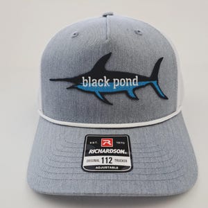 May include: Gray trucker hat with a white mesh back and a black and blue marlin design. The hat features the text "black pond" and a Richardson patch.