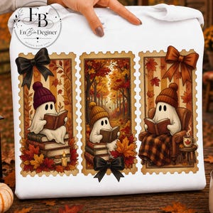 May include: A white sweatshirt featuring three rectangular stamp-style illustrations of ghosts reading books in an autumn forest setting. The ghosts wear knit hats, and the designs include maple leaves, stacks of books, a candle, and black bows.
