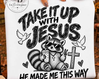 May include: A white sweatshirt featuring a black graphic of a raccoon wearing sunglasses, holding a drink, and making a peace sign. The design includes a cross, two doves, hearts, and the text "TAKE IT UP WITH JESUS HE MADE ME THIS WAY."