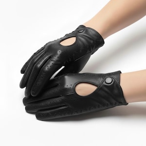 Puede incluir: Guantes de conducción de cuero negro con un gran recorte ovalado en el dorso de la mano y pequeñas perforaciones. Los guantes tienen un cierre de botón. El texto "LEATHERMED FORGE" es visible en la esquina superior izquierda.