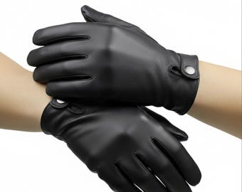 Pode incluir: Um par de luvas de couro preto com fecho de botão no pulso. As luvas são lisas e ajustadas, com recortes nas costas da mão. A marca "LEATHERMed FORGE" é visível no canto superior direito.