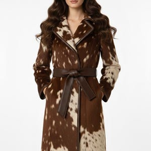 May include: A long, brown and cream-colored coat with a cowhide pattern. The coat has a notched collar, a matching belt, and the text "leathermed forge" at the top.