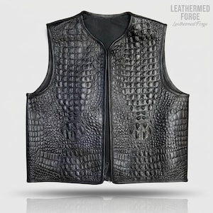Peut inclure: Gilet en cuir noir avec une texture peau de crocodile. Le gilet a un col en V et une fermeture éclair sur toute la longueur. La marque "Leathermed Forge" est imprimée en blanc en haut à droite. Sans manches.