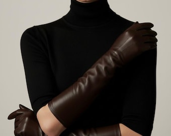 Könnte beinhalten: Lange, dunkelbraune Lederhandschuhe. Die Handschuhe reichen über die Ellbogen hinaus. Das Model trägt einen schwarzen Rollkragenpullover. Die Handschuhe haben eine satte, einfarbige Farbe und scheinen aus hochwertigem Leder zu sein.