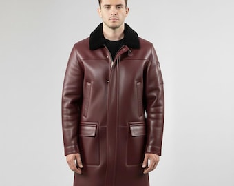 May include: A burgundy leather coat with a black shearling collar. The coat has a zip closure, two front pockets, and a small pocket on the left sleeve. The brand name "leathermed forge" is printed in the upper right corner.