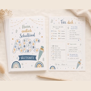 Könnte beinhalten: Ein Stapel Gästekarten und eine einzelne Karte mit dem deutschen Text Hurra, endlich Schulkind ABC GÄSTEKARTE. Das Design zeigt blaue, goldene und beige Illustrationen von Regenbögen, Sternen und einer Schultüte. Die Rückseite enthält Felder zum Ausfüllen für Wünsche und Ratschläge, mit dem Namen Marie am unteren Rand.