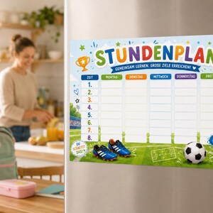 Könnte beinhalten: Ein rechteckiger magnetischer Stundenplan mit Fußball-Motiv, grünem Rasen, einem Fußball und blauen Fußballschuhen. Die Überschrift lautet STUNDENPLAN, GEMEINSAM LERNEN, GROBE ZIELE ERREICHEN, mit Spalten für die Wochentage von Montag bis Freitag.