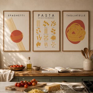 K&ouml;nnte beinhalten: Drei rechteckige Wandbilder in Holzrahmen mit Nudelillustrationen. Das linke Bild zeigt Spaghetti, das mittlere Bild zeigt verschiedene Nudelformen mit dem Text PASTA und das rechte Bild zeigt ein Nest aus Tagliatelle.