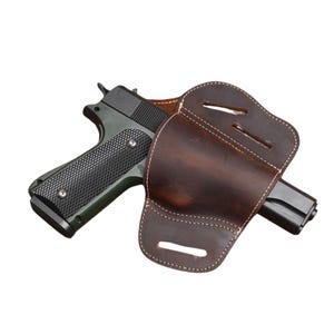 May include: A dark brown leather holster with a stitched design holds a black and green handgun. The handgun has a textured grip and a black slide. The holster is designed to fit the handgun securely.