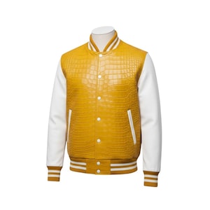 Könnte beinhalten: Senfgelbe Collegejacke mit weißen Ärmeln. Die Jacke hat ein strukturiertes, krokodilartiges Muster auf den Vorder- und Rückenteilen. Weiße und gelbe Streifen zieren Kragen, Manschetten und Saum. Die Jacke hat weiße Knöpfe.