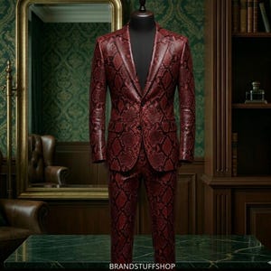Könnte beinhalten: Ein zweiteiliger Anzug mit Schlangenmuster in Rot, präsentiert auf einer Schaufensterpuppe. Der Anzug besteht aus einem einreihigen Sakko und einer passenden Hose. Der Text "BRANDSTUFFSHOP" ist im Bild zu sehen.