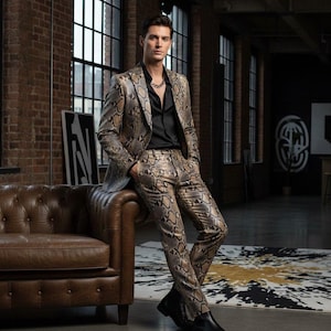 May include: A snakeskin-effect suit, comprising a blazer and matching trousers, worn with a black shirt and boots. The suit is in shades of brown and tan. A silver chain necklace is visible. The person is leaning against a brown leather sofa.