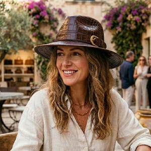 Sombrero fedora de piel marrón con relieve de cocodrilo y detalle de hebilla dorada, estilo safari.