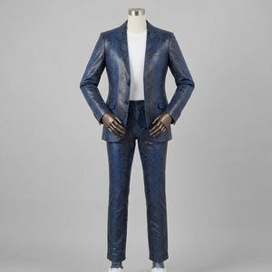 Może przedstawiać: Niebieski garnitur z wzorem skóry węża prezentowany na manekinie. Garnitur składa się z marynarki z zapięciem na dwa guziki i pasujących spodni. Pod marynarką widoczny jest biały t-shirt. Garnitur jest zestawiony z białymi trampkami.